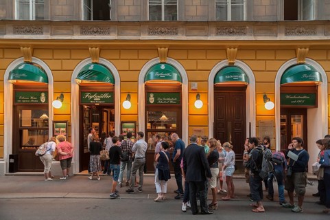 Tourists wait in long queues in front of the famous Schnitzel restaurant Figlmuller