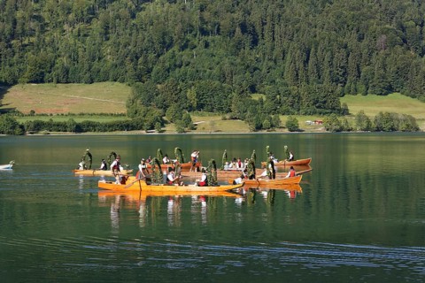 Locals wearing traditional costumes in decorated wooden Platte boats