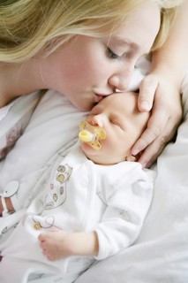 Big sister kissing her newborn brother