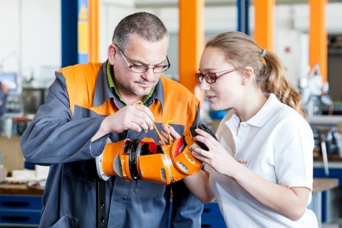 Instructor explaining a robot hand to a trainee for mechatronics assembly work