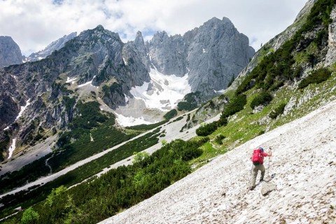 Female hiker crossing a snowfield on the Wilder-Kaiser-Steig hiking trail