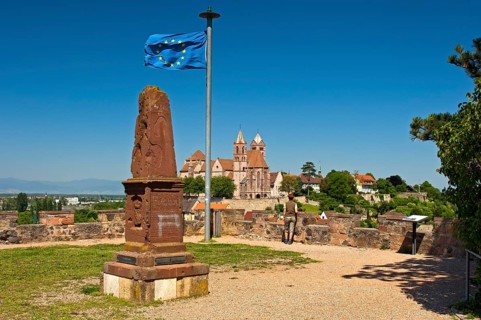 Obelisk and the European flag on Eckartsberg hill in front of the historic centre of Breisach with St. Stephansmunster Cathedral
