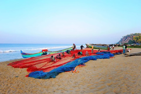 Fishermen repairing nets on the beach
