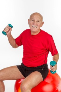 Elderly man sitting on a stability ball holding small dumbbells