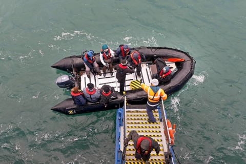 Tourists being helped out of an inflatable boat