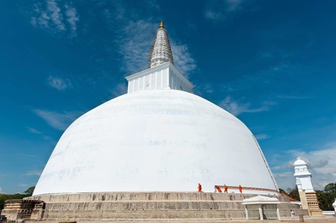 Monks tying a cloth around a large white stupa