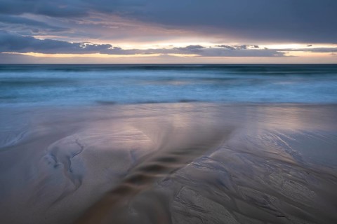 Water flows into the sea at the sandy beach