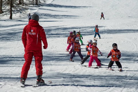 Children ski lessons with instructor on the piste