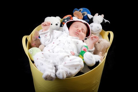 Baby sleeping in a bucket full of stuffed animals