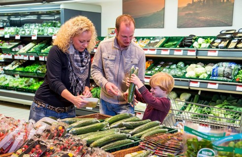 Family shopping with a shopping trolley in the fruit and vegetables department of a supermarket