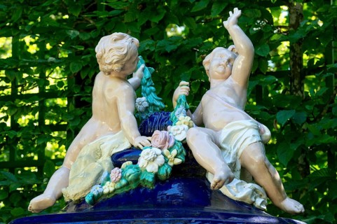 Putti on an ornamental vessel made of glazed ceramic