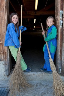 Two sisters holding stable brooms