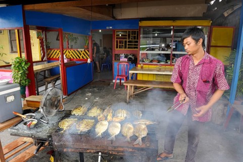 Javanese man grilling fish in a restaurant