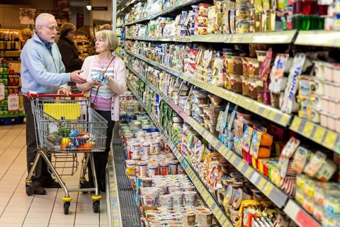 Senior couple shopping with a shopping trolley in the refrigerated dairy section in a supermarket