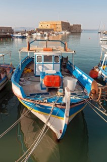 Fishing boat in front of Koules Fortress or Rocca al Mare
