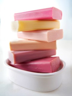 Bars of coloured hand made soap piled in a soap dish