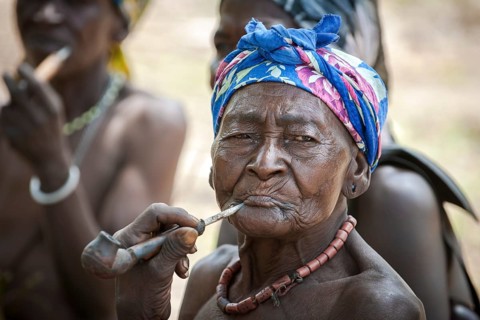 An elderly woman from the Koma people smoking a pipe