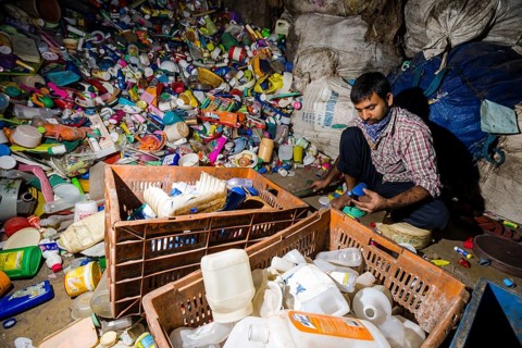 Worker sorting out plastic garbage for recycling