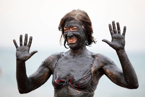 Female tourist covered in salty mud from the Dead Sea
