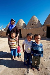 Mother and children in front of their beehive adobe buildings