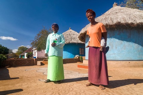Man and woman with child standing in front of adobe houses