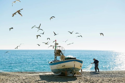 Fisherman with a fishing boat on the beach of Noli