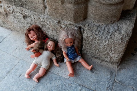 Three forgotten children's dolls beside a medieval column