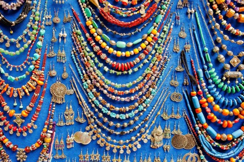 Display of various necklaces and earrings with glass beads and traditional Arab and Berber patterns