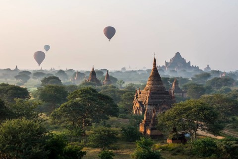 Hot air balloons over the landscape in the early morning fog