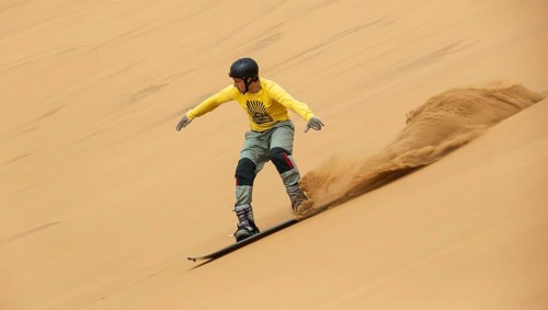 Sand boarding in the dunes of the Namib Desert