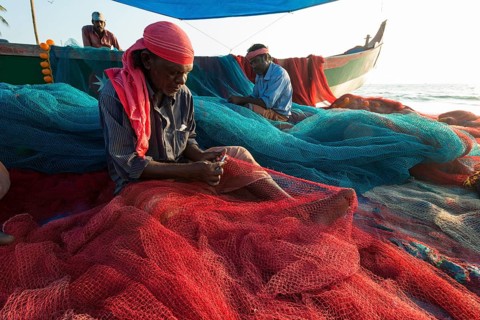 Fishermen repairing fishing nets on the beach