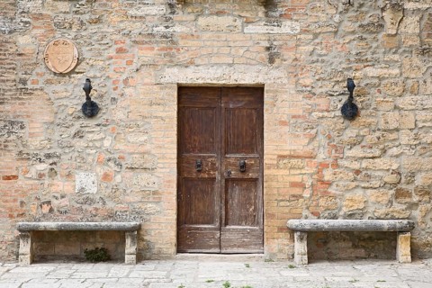 Two stone benches standing next to the door of an old house