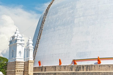 Monks tying a cloth around a large white stupa