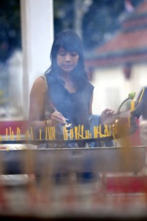 Woman lighting candles outside the Wat Phra Si Rattana Mahathat Temple