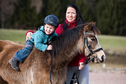 Young child wearing a riding helmet sitting bareback on a pony