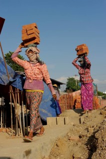Female construction workers carry bricks on their heads