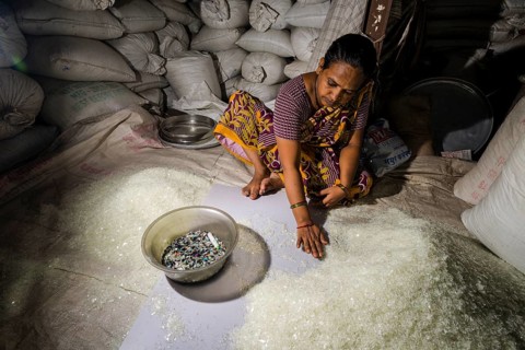 Woman sorting out shredded white plastic garbage for recycling