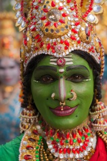 Hindu temple dancer wearing gold jewelry with his face painted green