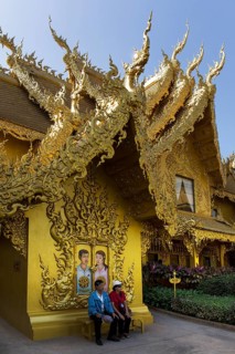Tourists sitting in front of the gilded toilet house at Wat Rong Khun