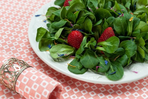 Lamb's lettuce with strawberries and flower petals served on a plate