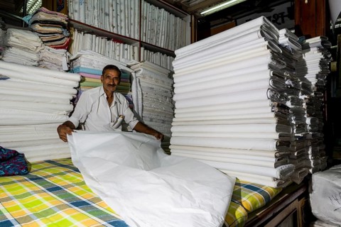 A salesman is displaying white material at Mangaldas Market