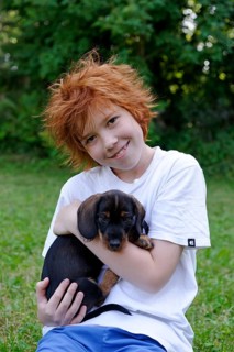 Boy holding wire-haired dachshund puppy in his arms