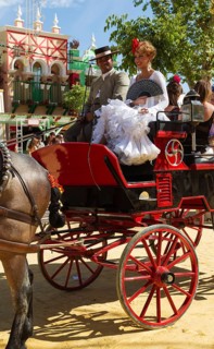 Dressed up coachman and young lady wearing a gypsy dress at the Feria del Caballo Horse Fair