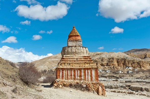 Colourfully decorated Buddhist stupa on a track in a vast landscape