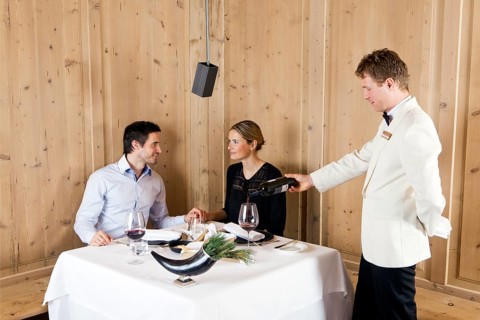 Man and woman in a restaurant waited on by a waiter
