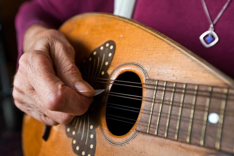 Hand of an elderly woman playing a mandolin
