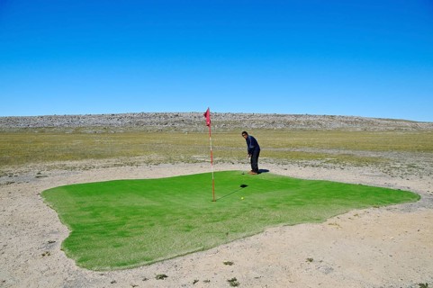Man hitting a golf ball on the northernmost golf course in the world