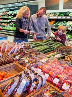 Family shopping with a shopping trolley in the fruit and vegetables department of a supermarket