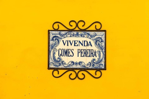 A blue and white plate with the name of the house at the entrance of a building
