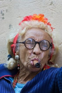 Old woman wearing coulorful clothes posing with a cigar